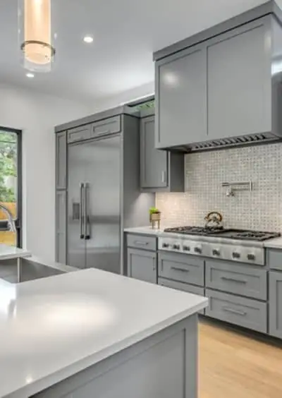 A grey painted scullery with a professional range and a woven tile backsplash