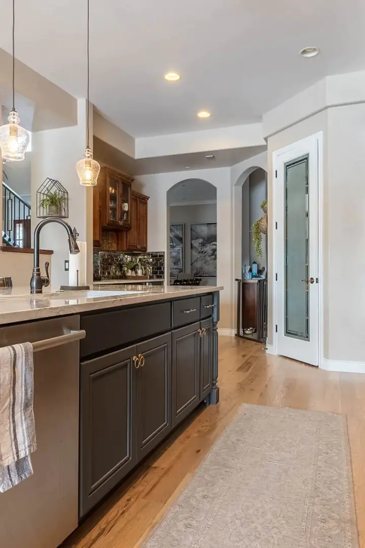 Dark painted butler’s pantry cabinetry with an arched glass door leading to a dining room