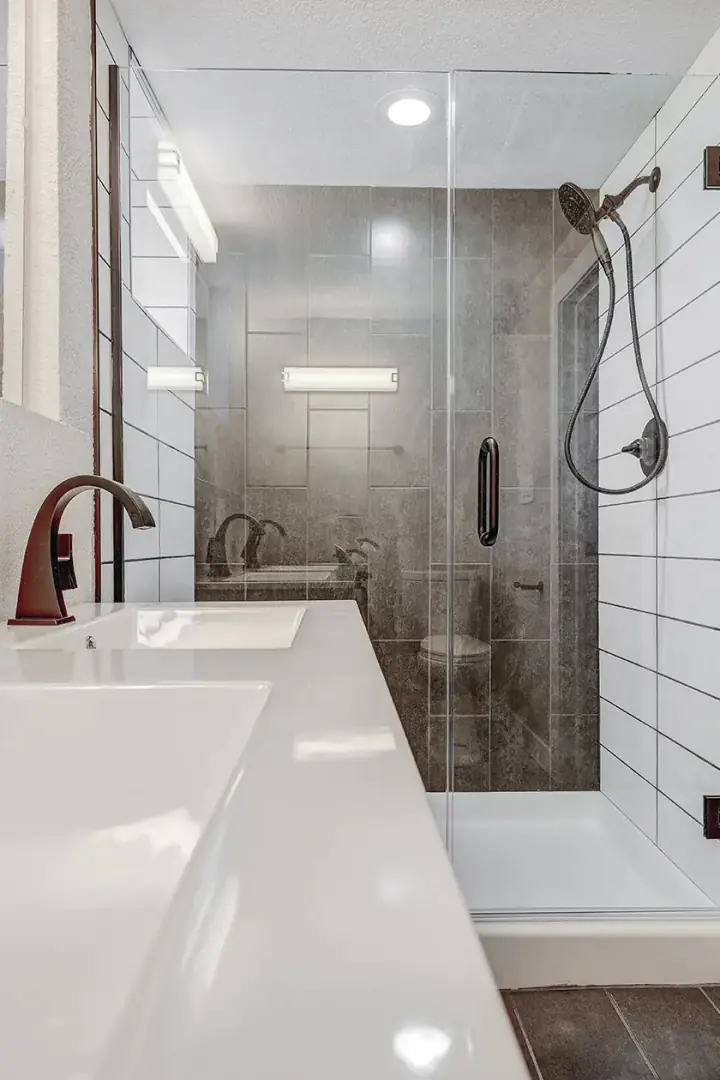 Curbless walk-in shower in honed grey porcelain beside a long double vanity in a bright bathroom
