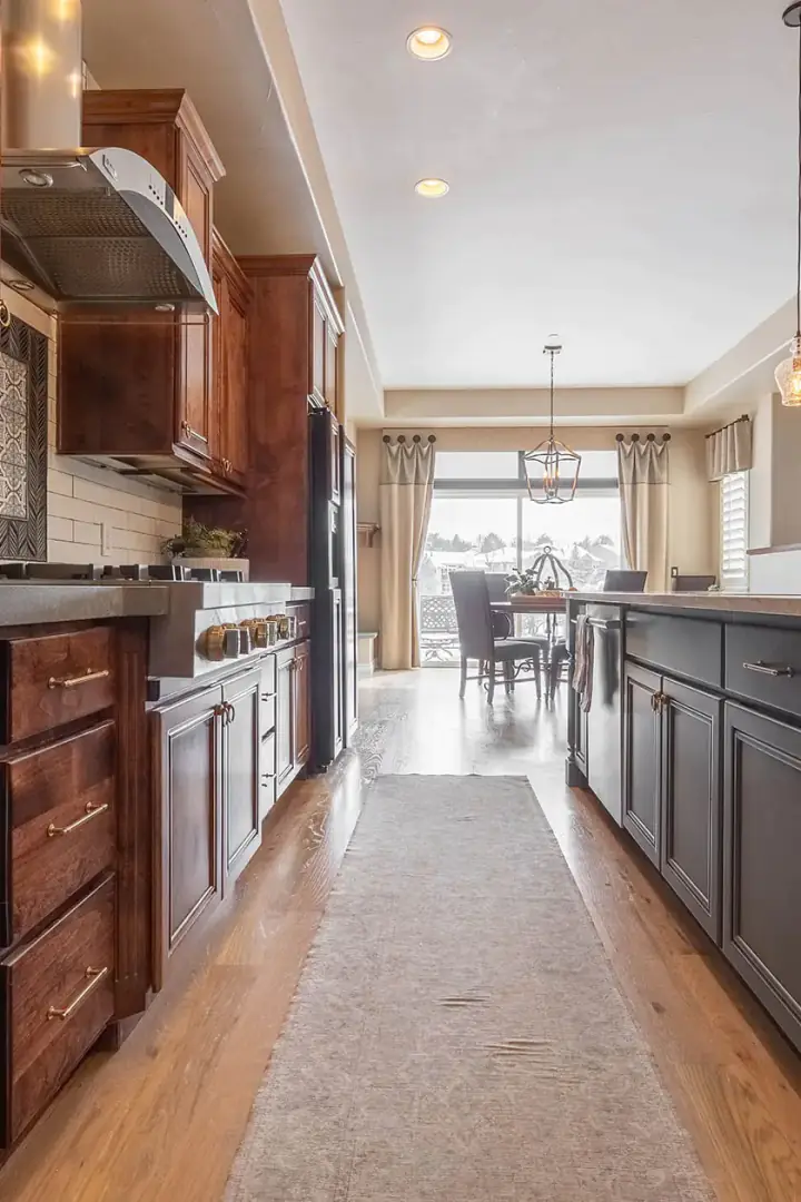 Two-tone galley kitchen with white oak cabinets on one wall and charcoal cabinets on the other